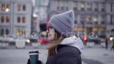 一个穿着黑色夹克和帽子的年轻女孩手里拿着咖啡在美丽的<strong>上海</strong>走来走去